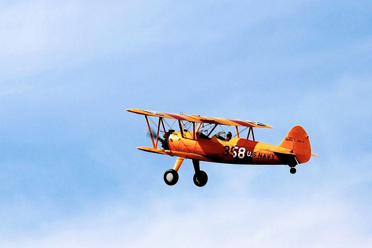 Orange biplane in blue sky