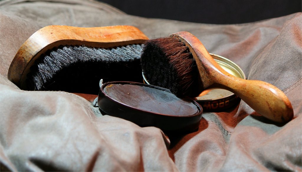 A shoe brush, buffing crush and open shoe polish all together on a cloth