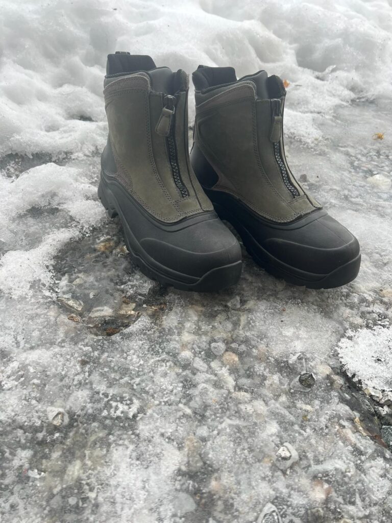 Pair of winter boots with zippers on ice surface.