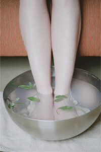 Picture of two legs getting a foot bath in a metal bowl